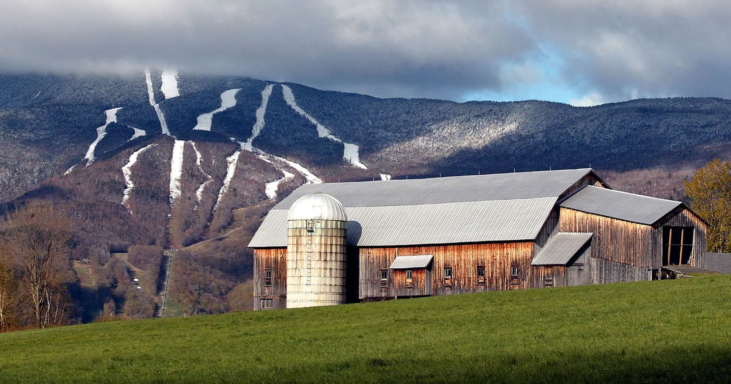 Barn with ski trails on mountain backdrop in Mad River Valley