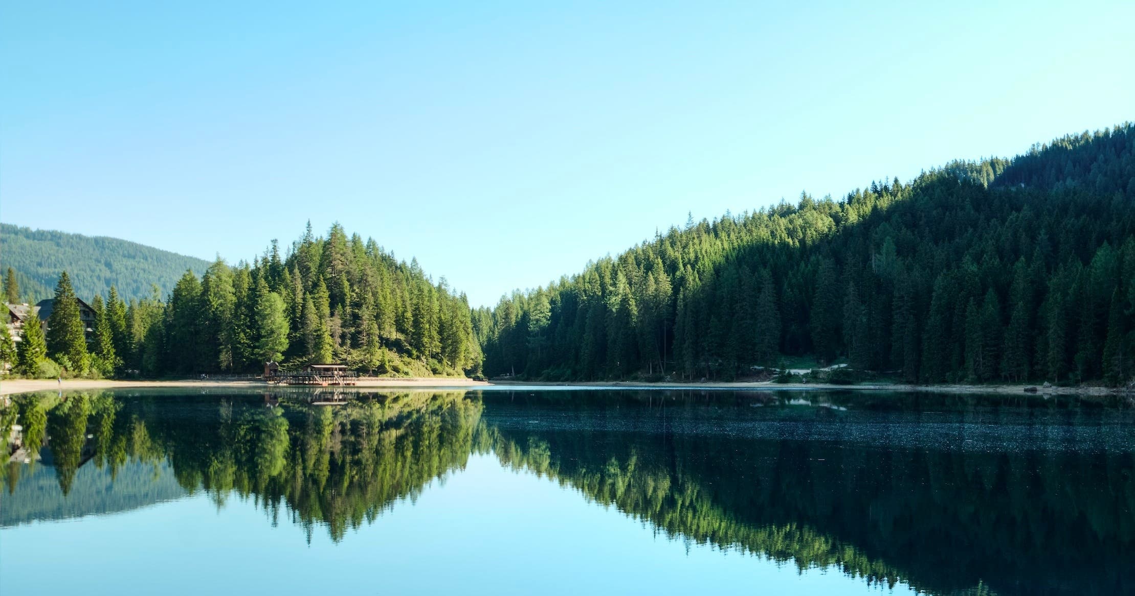 Calm alpine lake with forest reflection ideal for boating