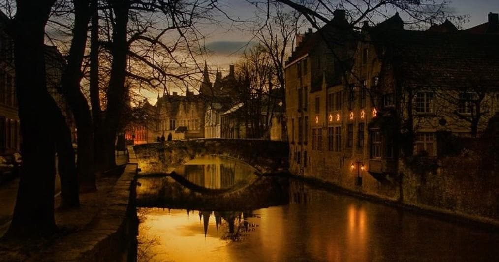 Tranquil canal at dusk with historic houses and walking paths