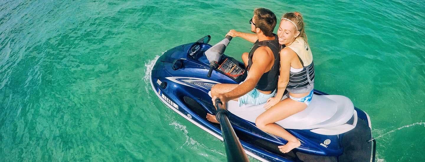 Couple riding jet ski over emerald water, high-angle adventure photo