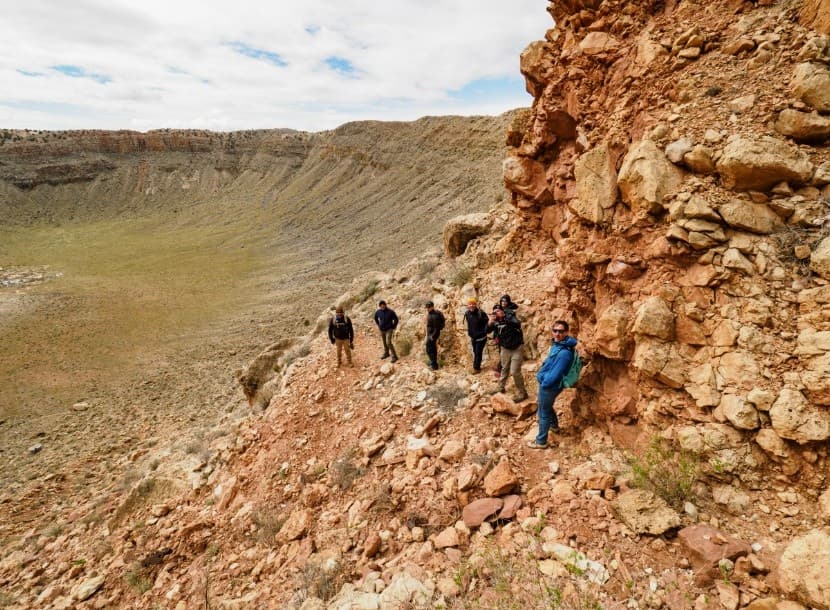 Group traversing rocky ledge at Meteor Crater rim surveying