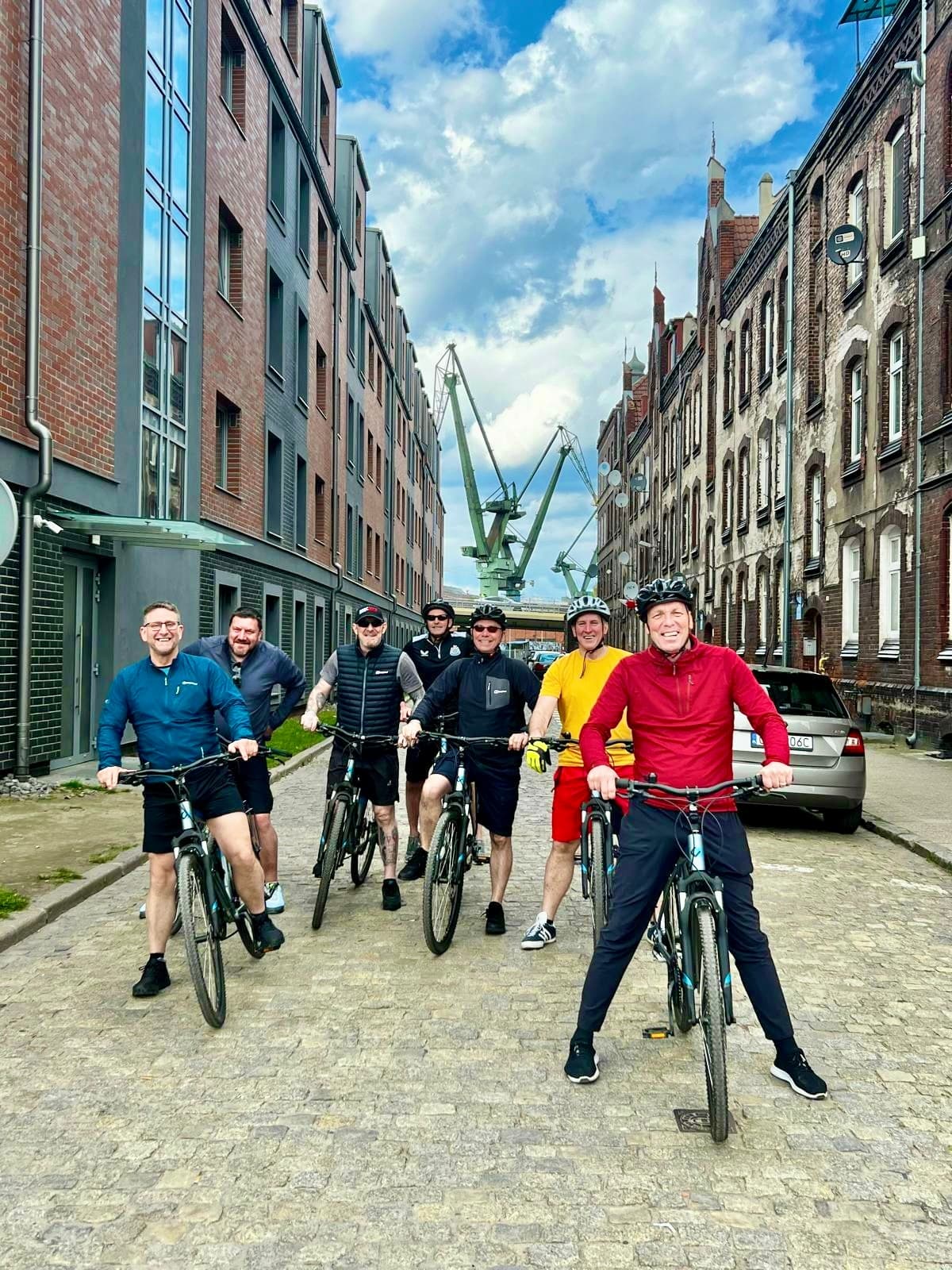 Guided bike tour group riding through historic cobblestone street