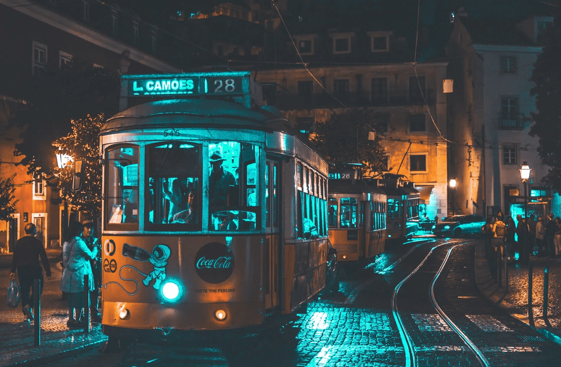 Historic Lisbon tram at night on wet cobblestone streets, urban ride