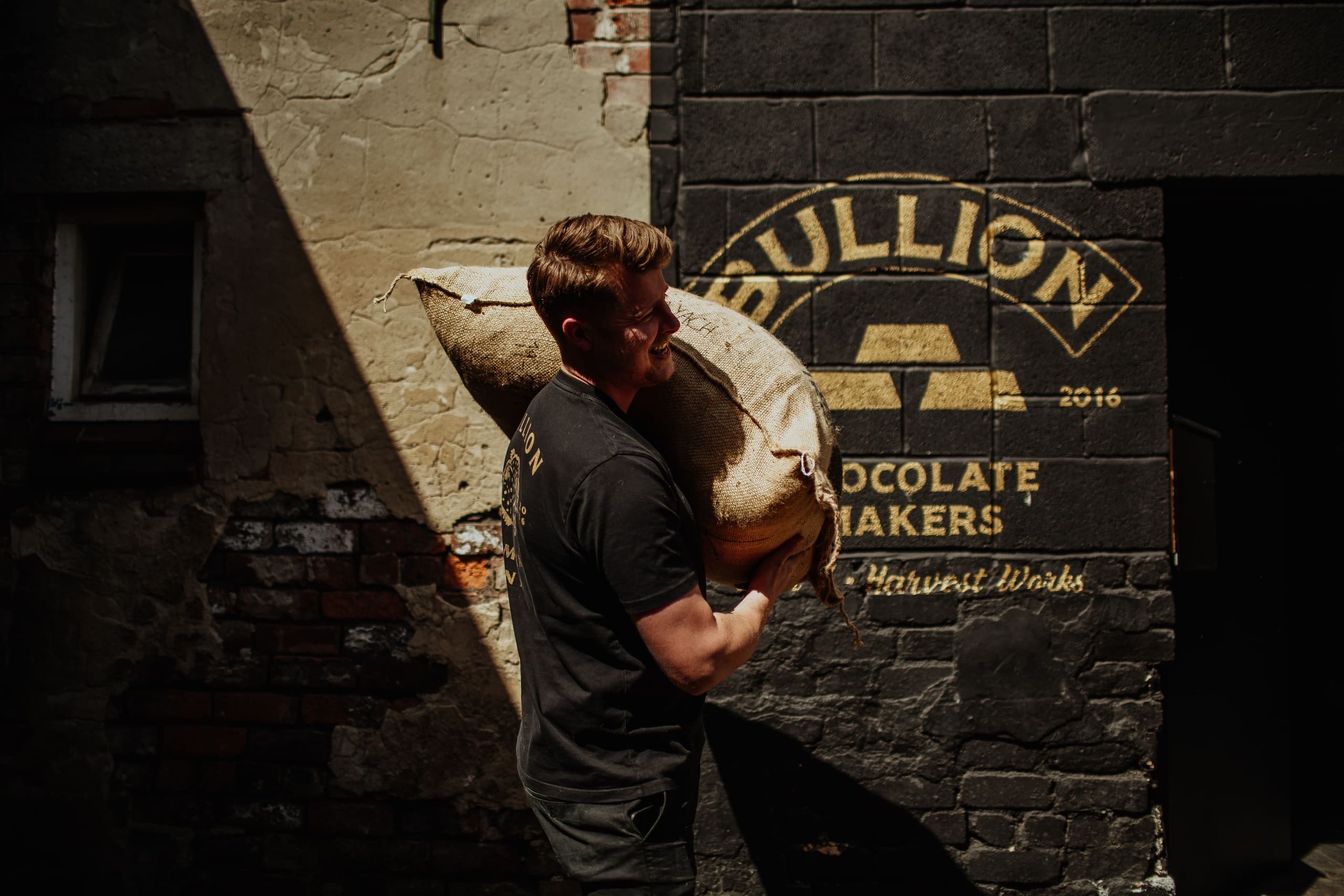 Man carrying large cocoa sacks outside Bullion Chocolate shop
