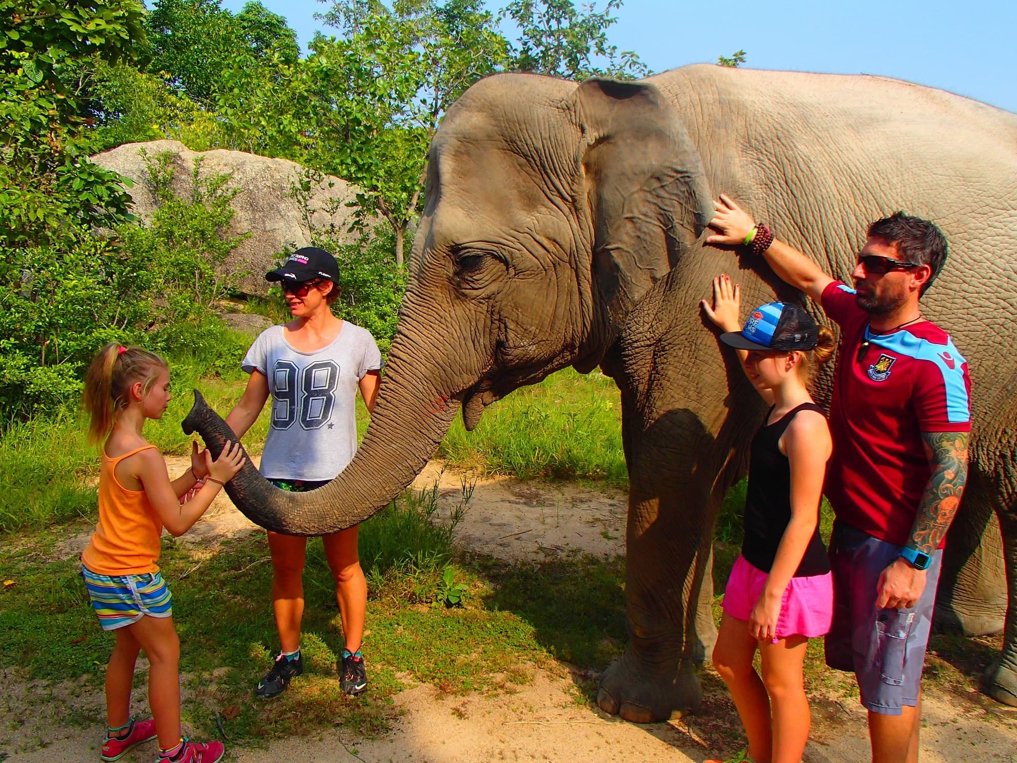 Family interacting with an elephant at an outdoor sanctuary in Thailand