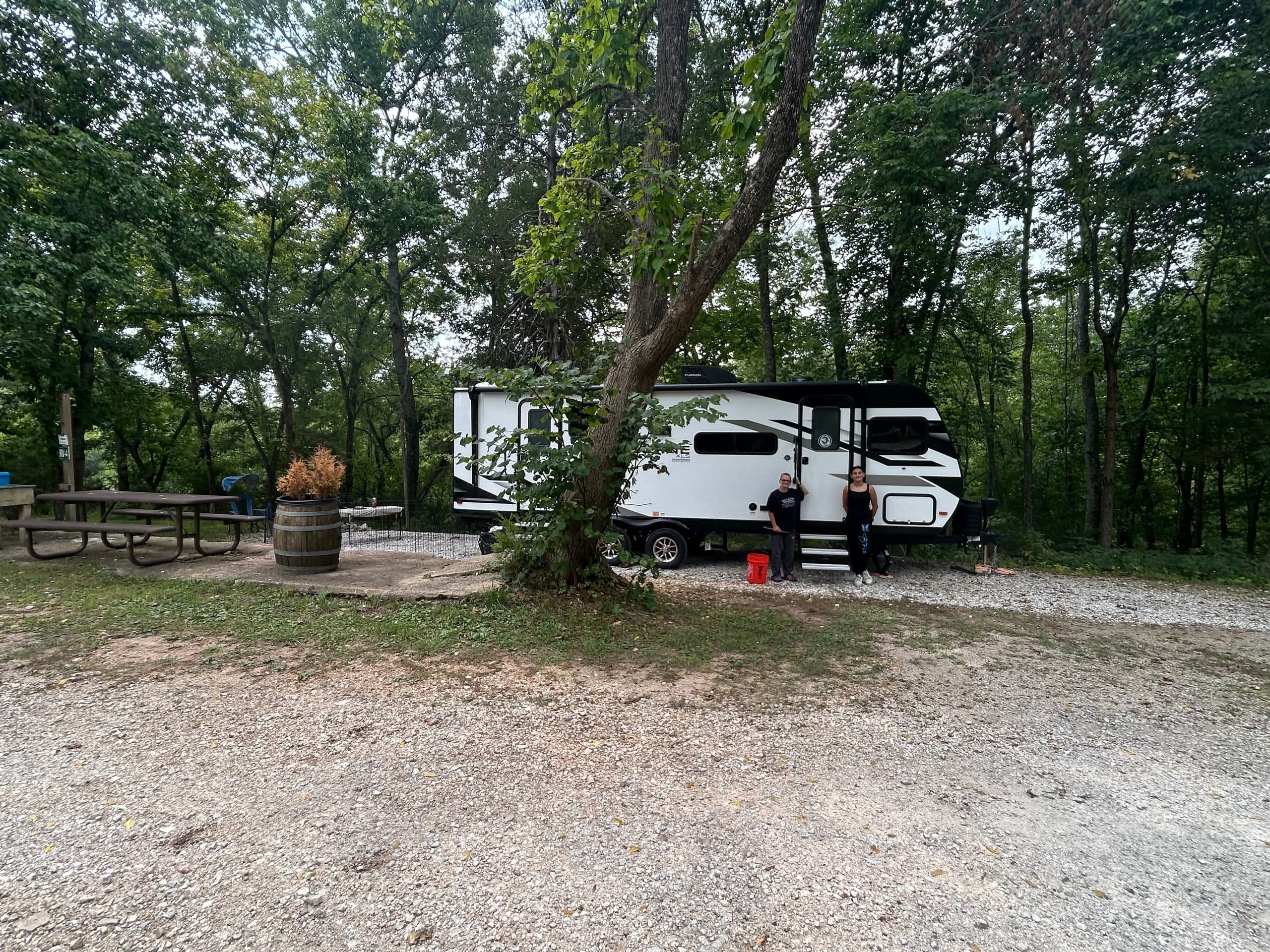 Gravel campsite drive beneath mature trees, RV parking area