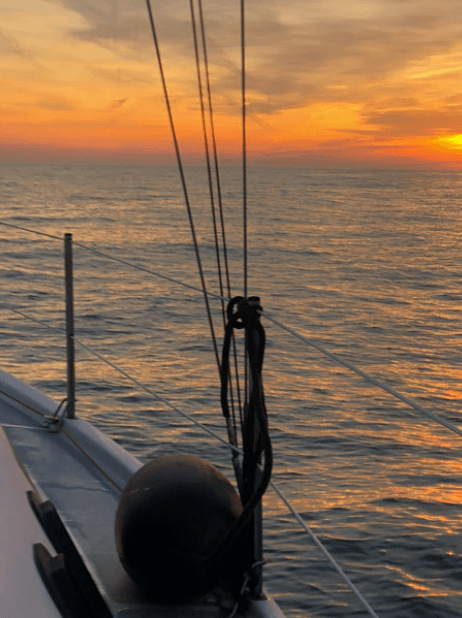 Sunset view from sailboat bow with calm sea horizon