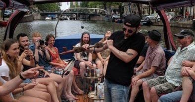 Friends partying on open canal boat tour in Amsterdam city