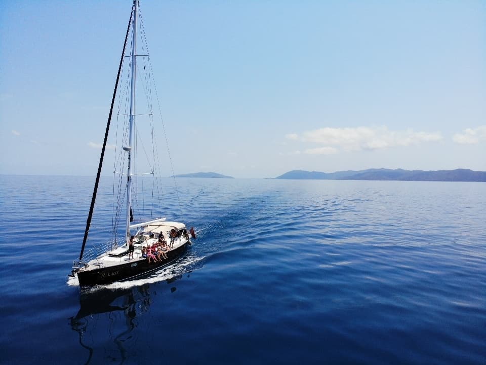 Sailboat cruising turquoise Whitsundays waters under clear sky