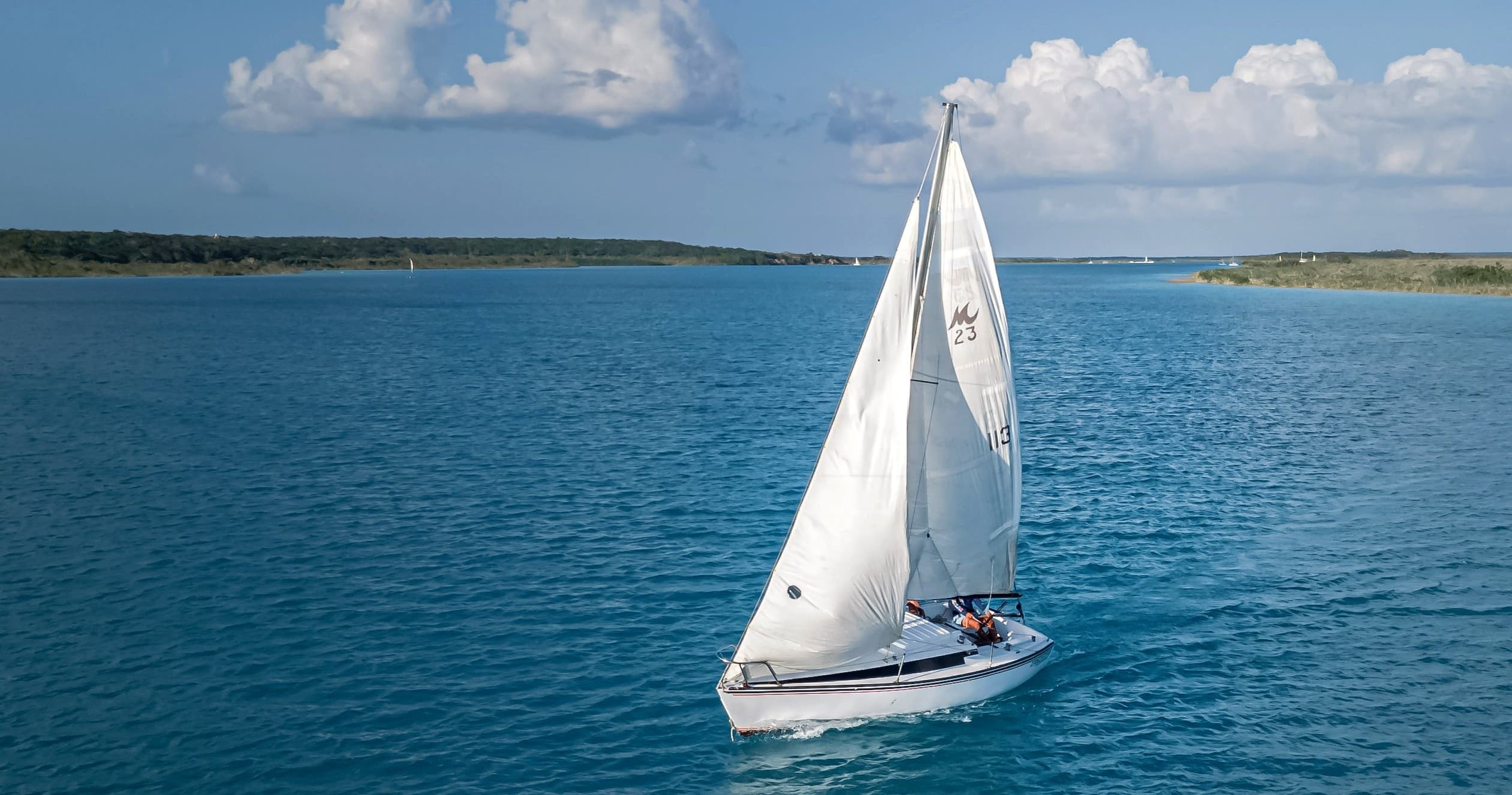 Single white sailboat cruising on deep blue open ocean waters