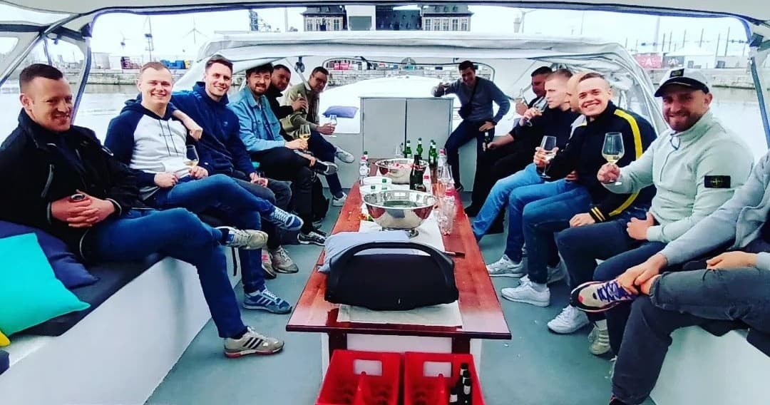 Friends seated on covered party boat cruising a calm harbor