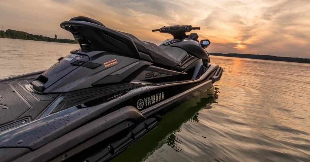 Yamaha jet ski cruising on lake at sunset, scenic watersport