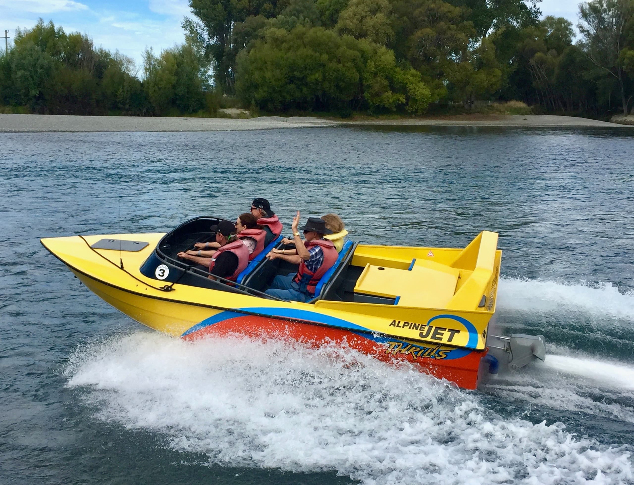 Close-up yellow jet boat ride on riverbank with excited guests