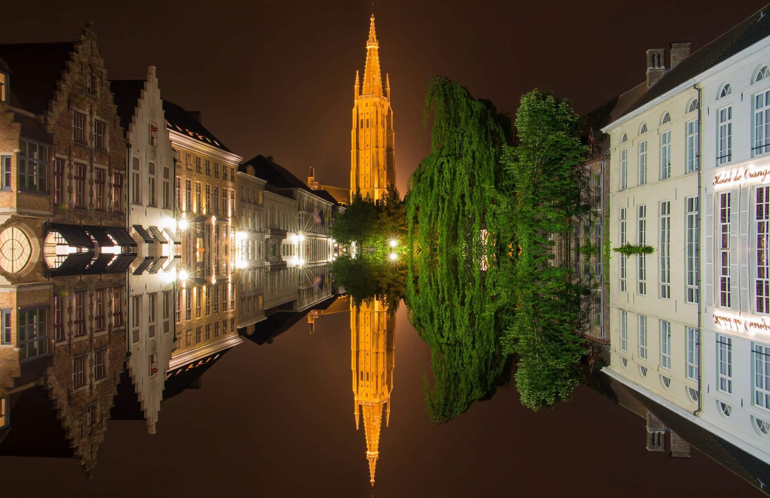 Nighttime canal reflection in Bruges with illuminated belfry