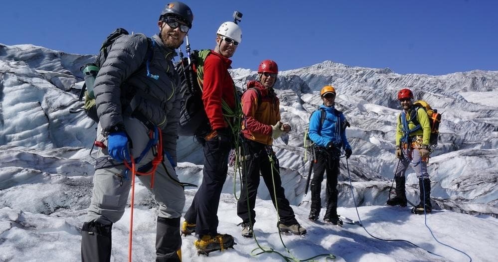Guided glacier climb group roped together on icy terrain