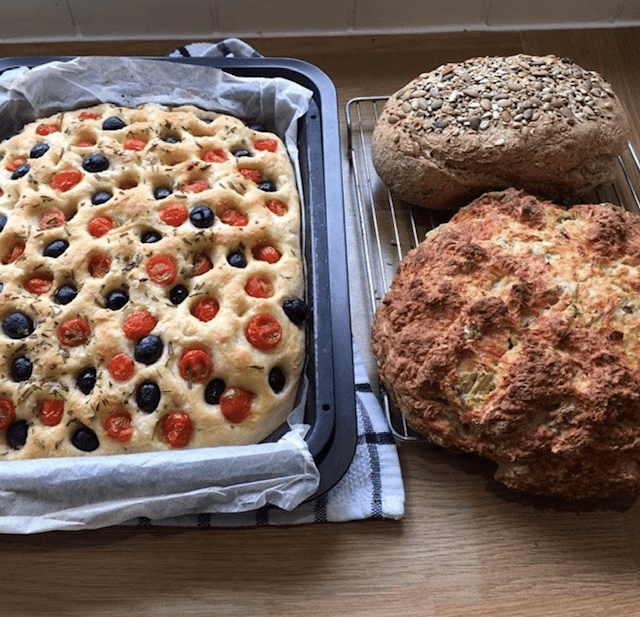 Focaccia and rustic loaves on wooden counter for baking