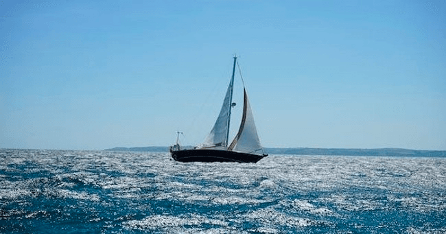 Solo sailboat navigating choppy sea under clear daytime sky