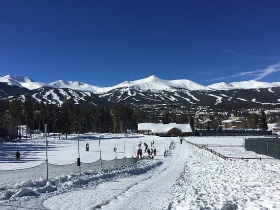 Groomed ski run with mountain peaks under clear blue sky