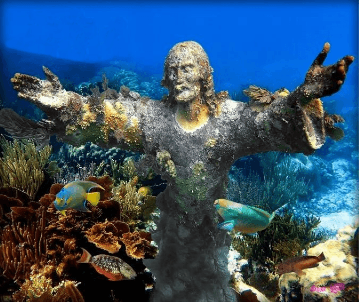 Divers exploring submerged Christ statue and coral reef