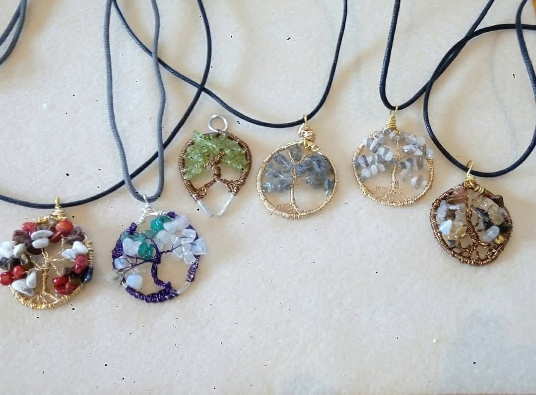 Assorted tree of life gemstone pendants on display table
