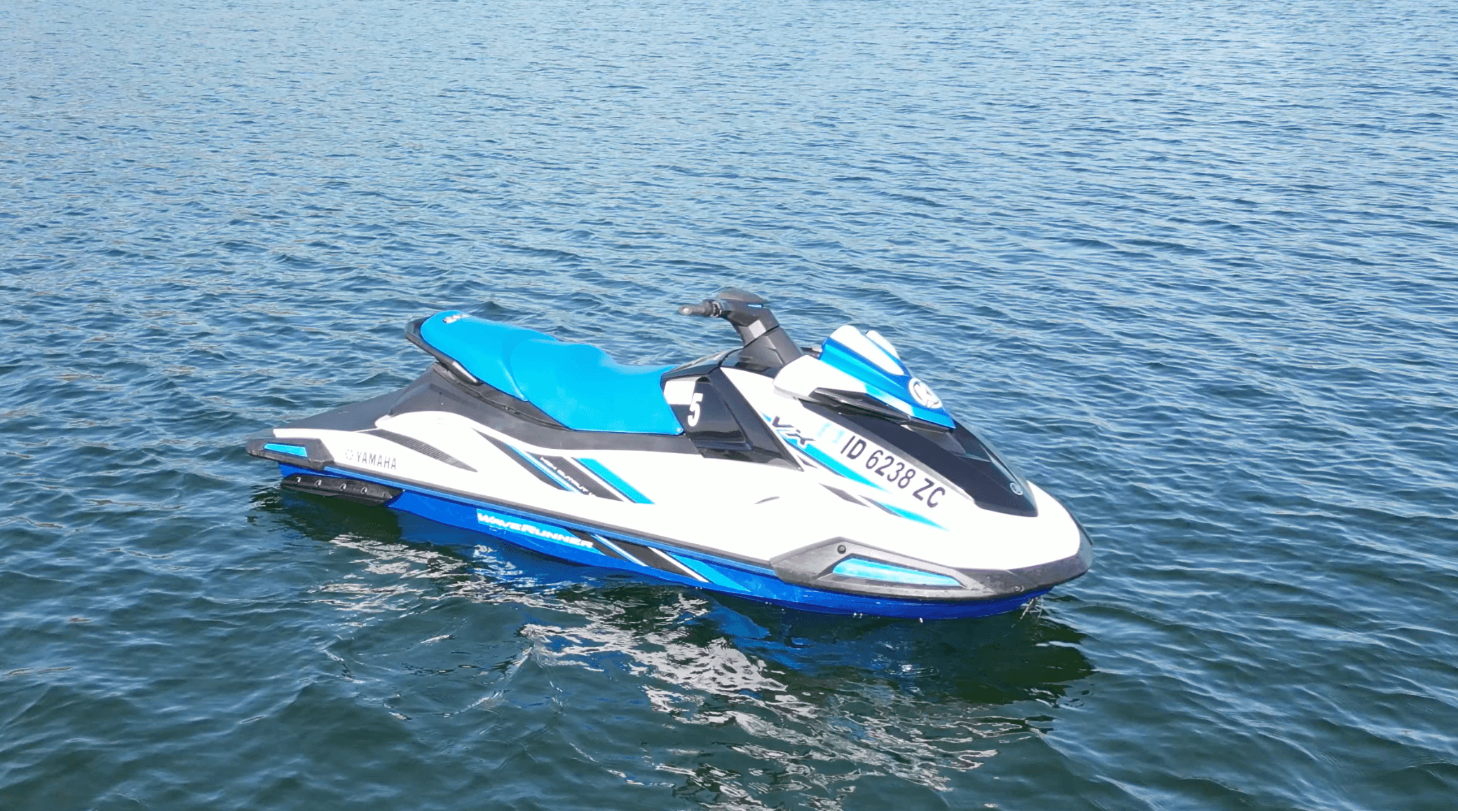 Blue jet ski zipping across open lake water on sunny day