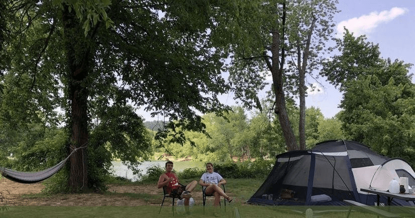 Family tent campsite under trees with hammock and chairs
