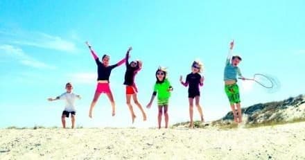Kids jumping on sunny St. George Island beach enjoying family fun