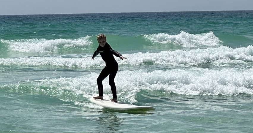 Surfer riding small Gulf of Mexico waves near shoreline