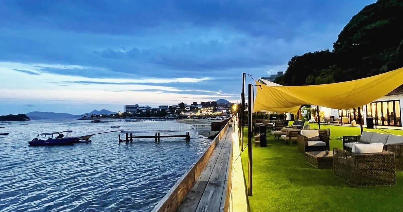 Sunset waterfront pier with lounge seating over calm ocean bay