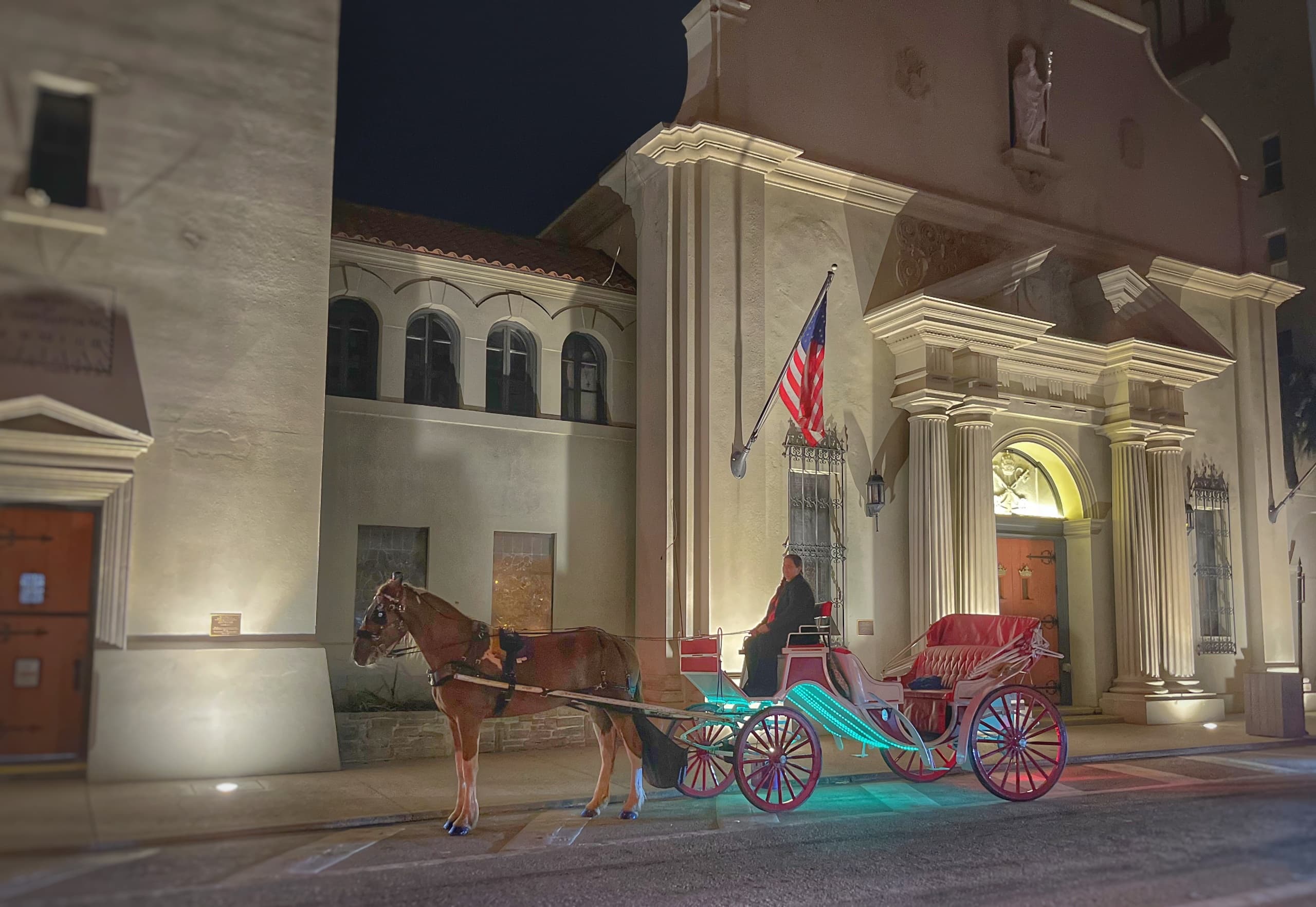 Evening horse-drawn carriage tour in front of historic coastal building