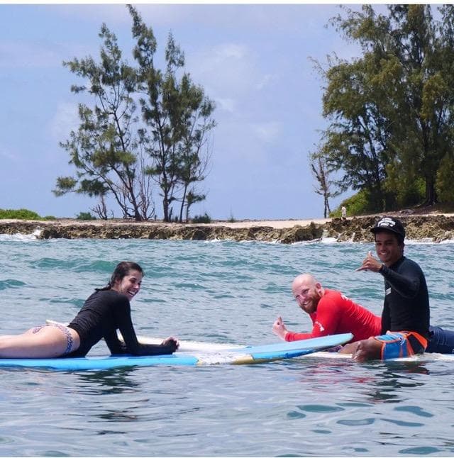 Students practicing prone surfing with instructor in Oahu reef