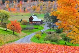 Country cottage amid colorful fall foliage, rural valley