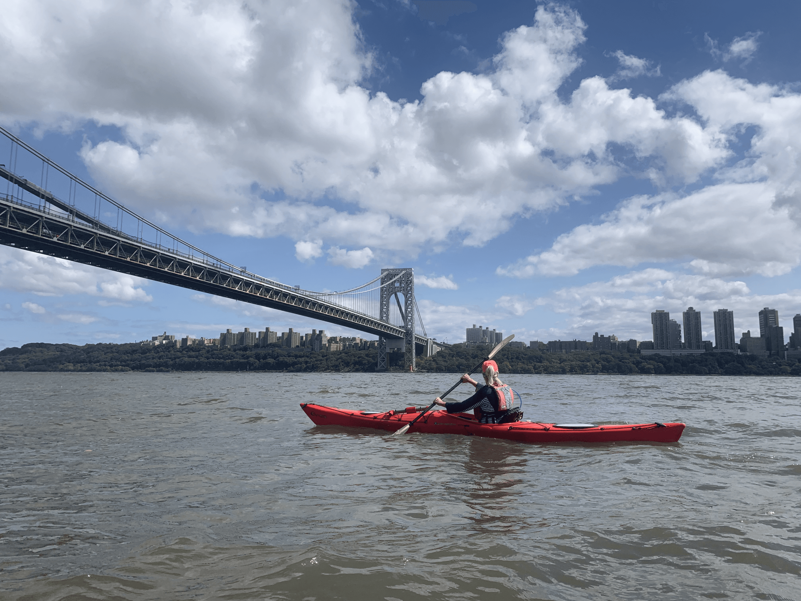 Standup paddleboarder in front of Manhattan skyline at sunset