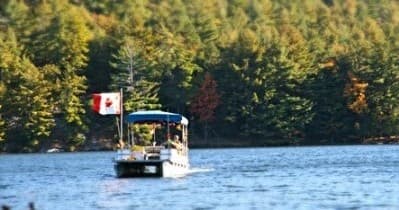Small tour boat with Canadian flag on calm island lake