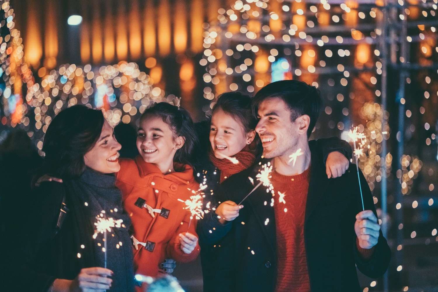 Family celebrating outdoors with sparklers at nighttime festival