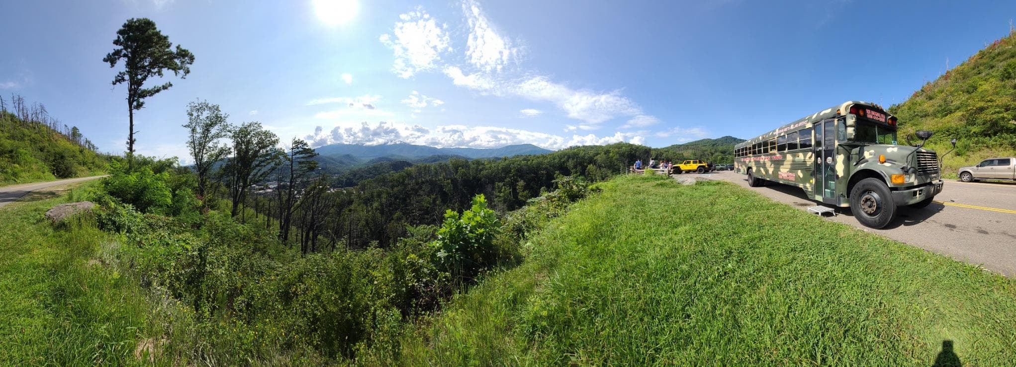Panoramic hillside bus tour with mountains and green valley
