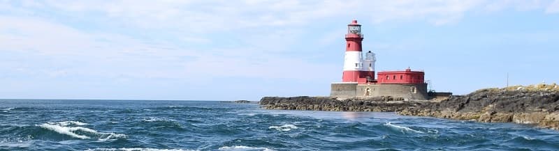 Coastal lighthouse and rocky shore at Farne Islands, sea view