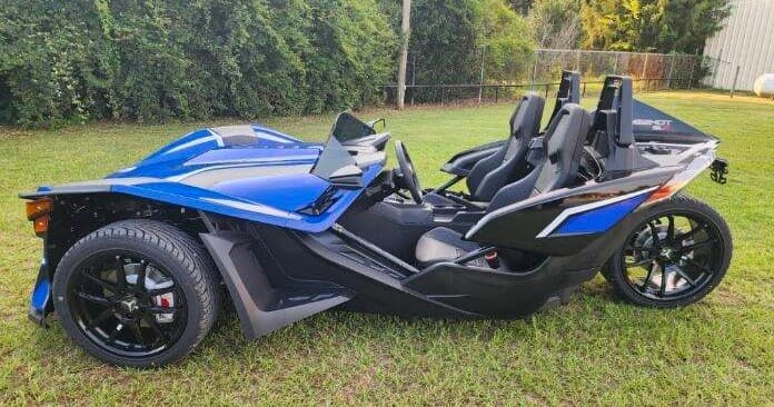 Blue Polaris Slingshot side profile on grassy field