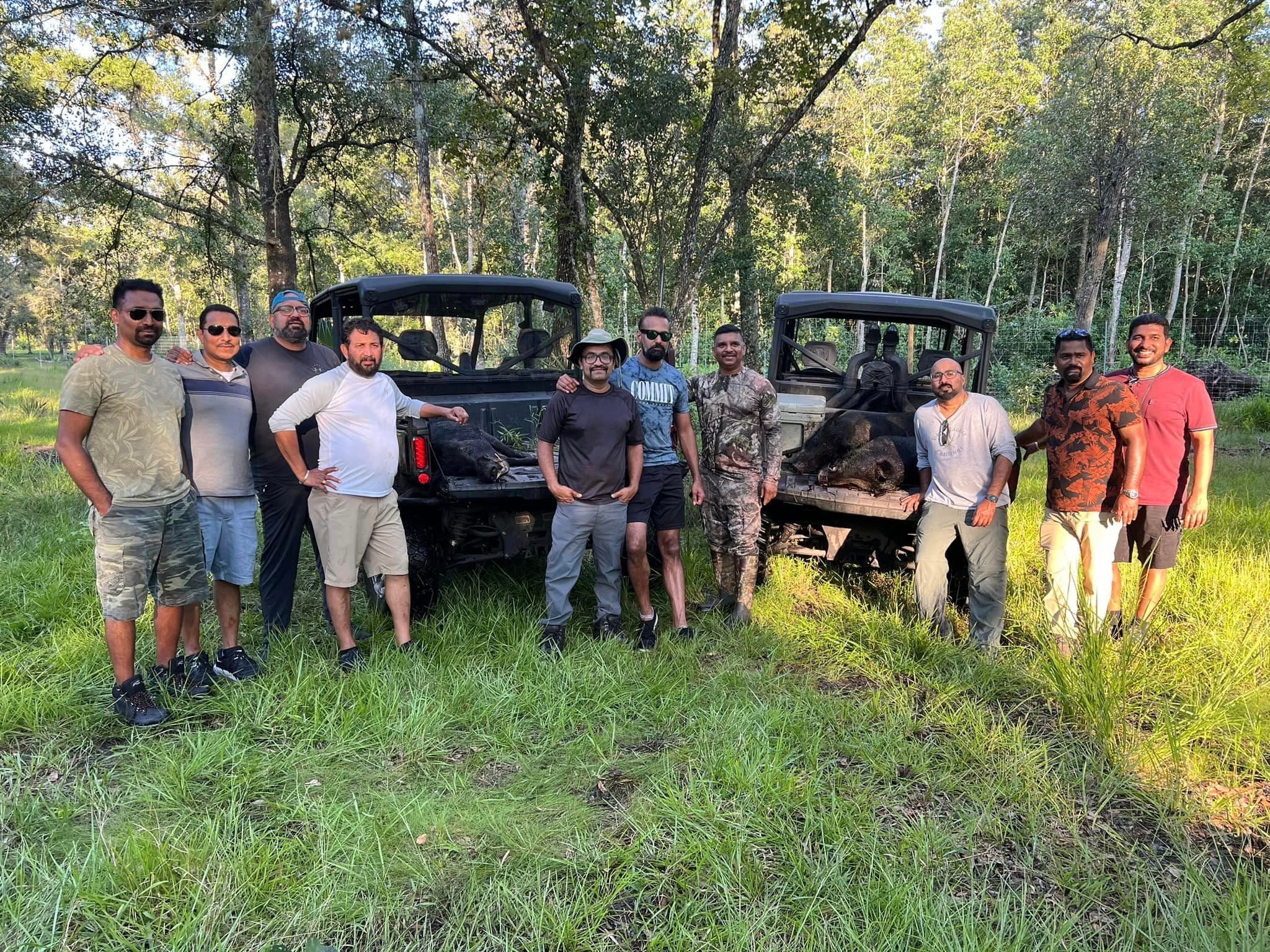 Hunting party posing with off-road UTVs in pine forest clearing