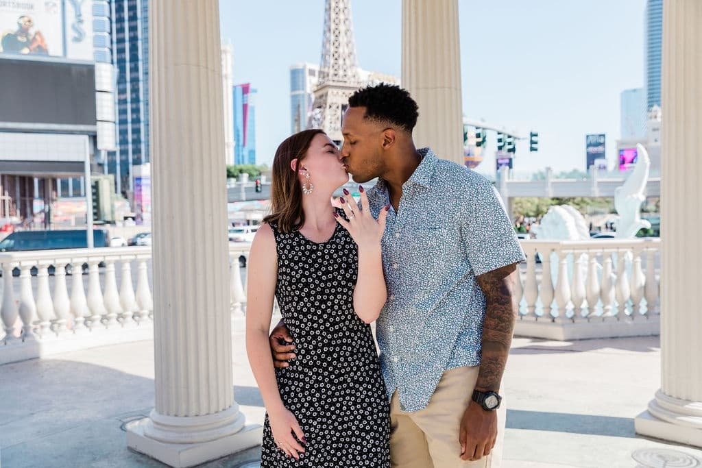 Couple kissing by classical columns on sunny Las Vegas promenade