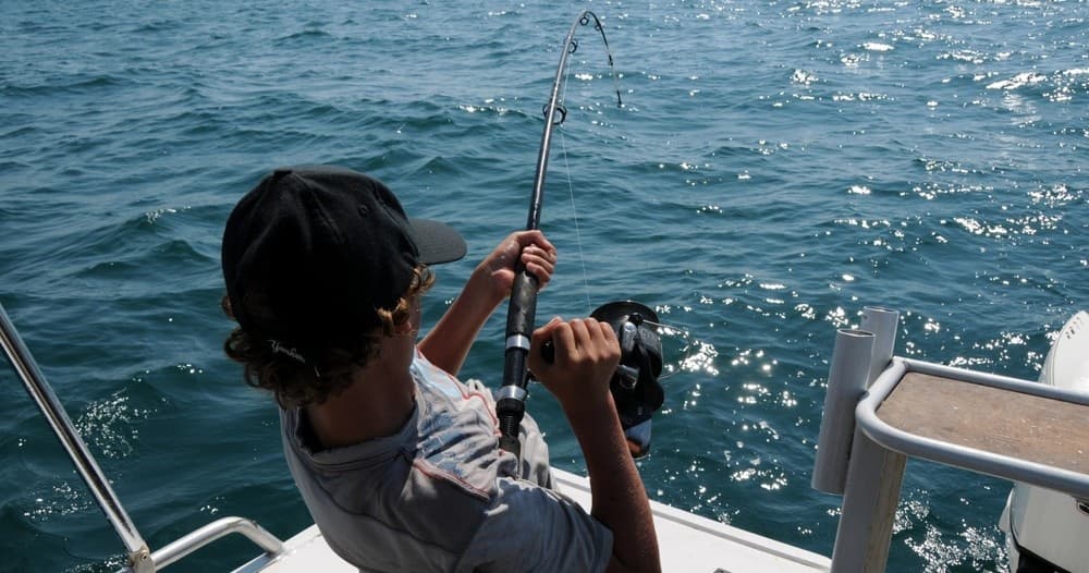 Angler reeling in fish from boat on choppy open ocean