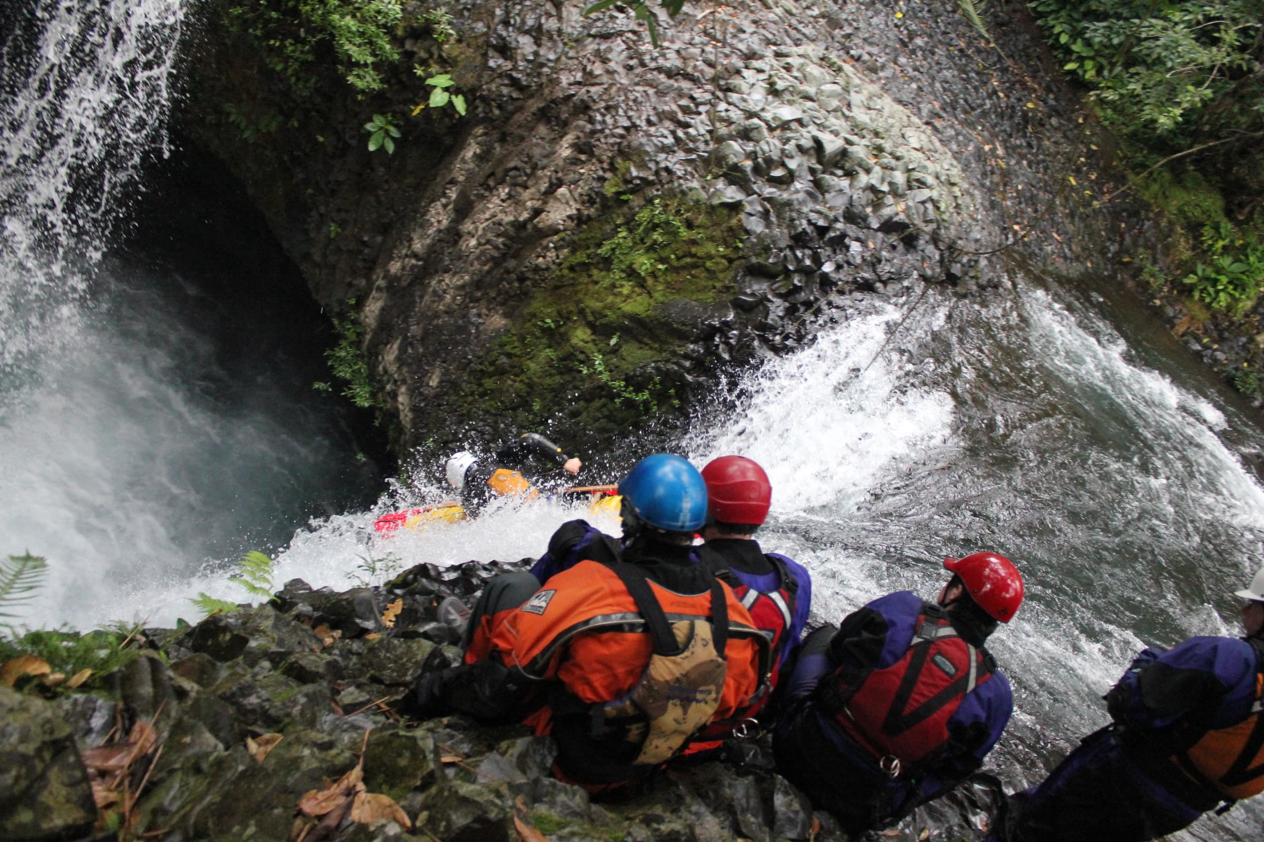 Rescue team navigating narrow waterfall canyon during descent