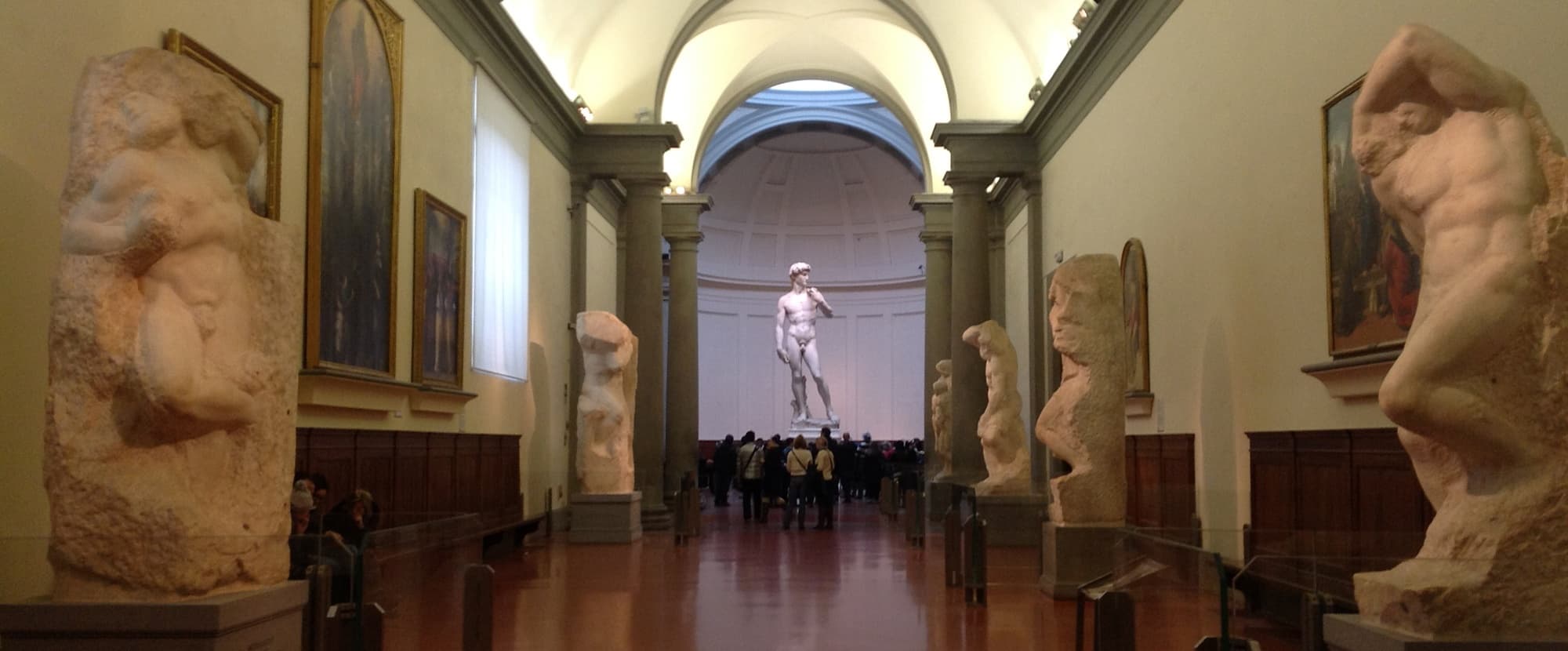 Grand museum hall with sculpted statue at end, art viewing tour