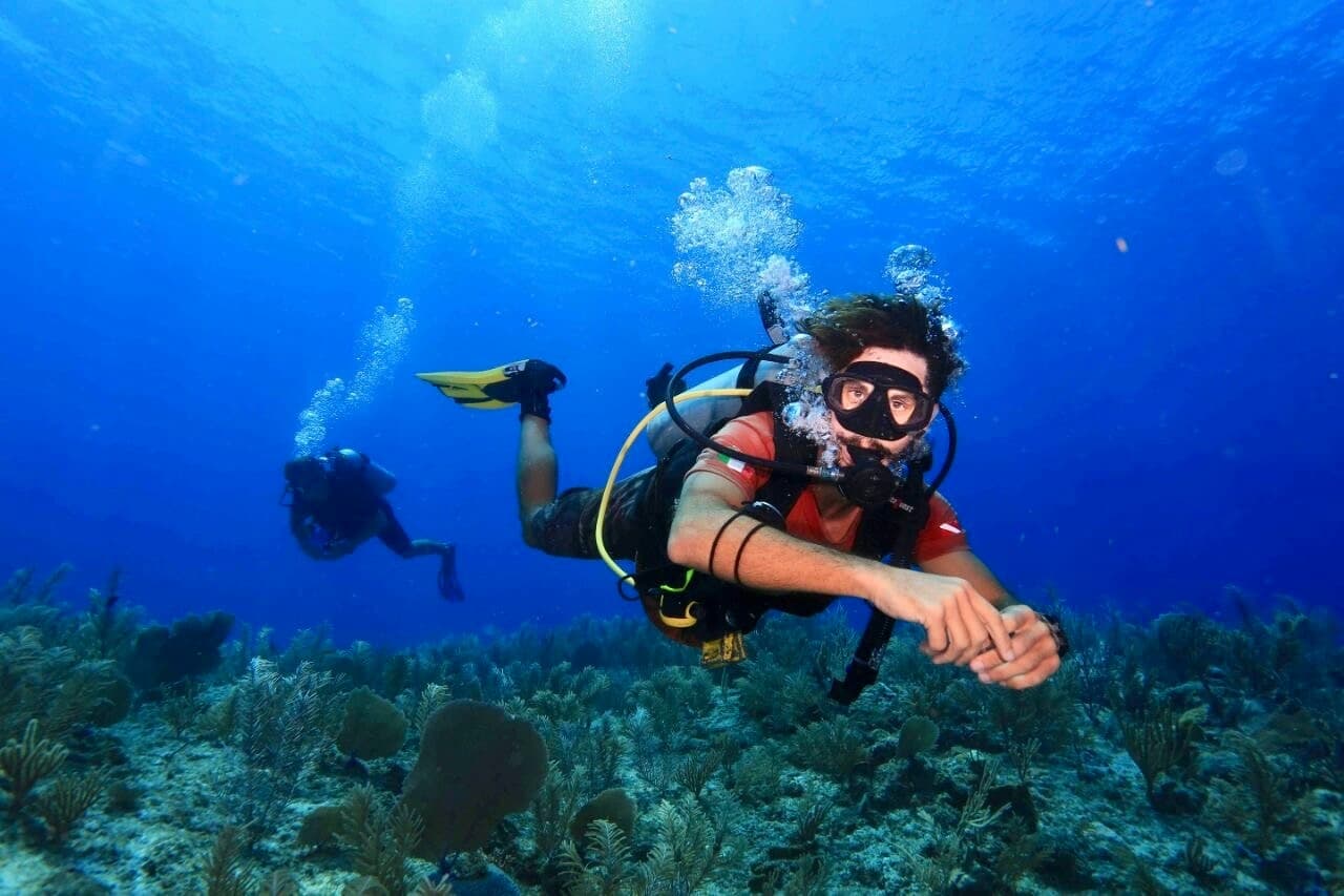 Single scuba diver cruising above reef in clear blue ocean