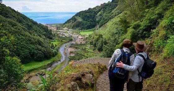 Hikers overlooking lush river valley on scenic mountain trail