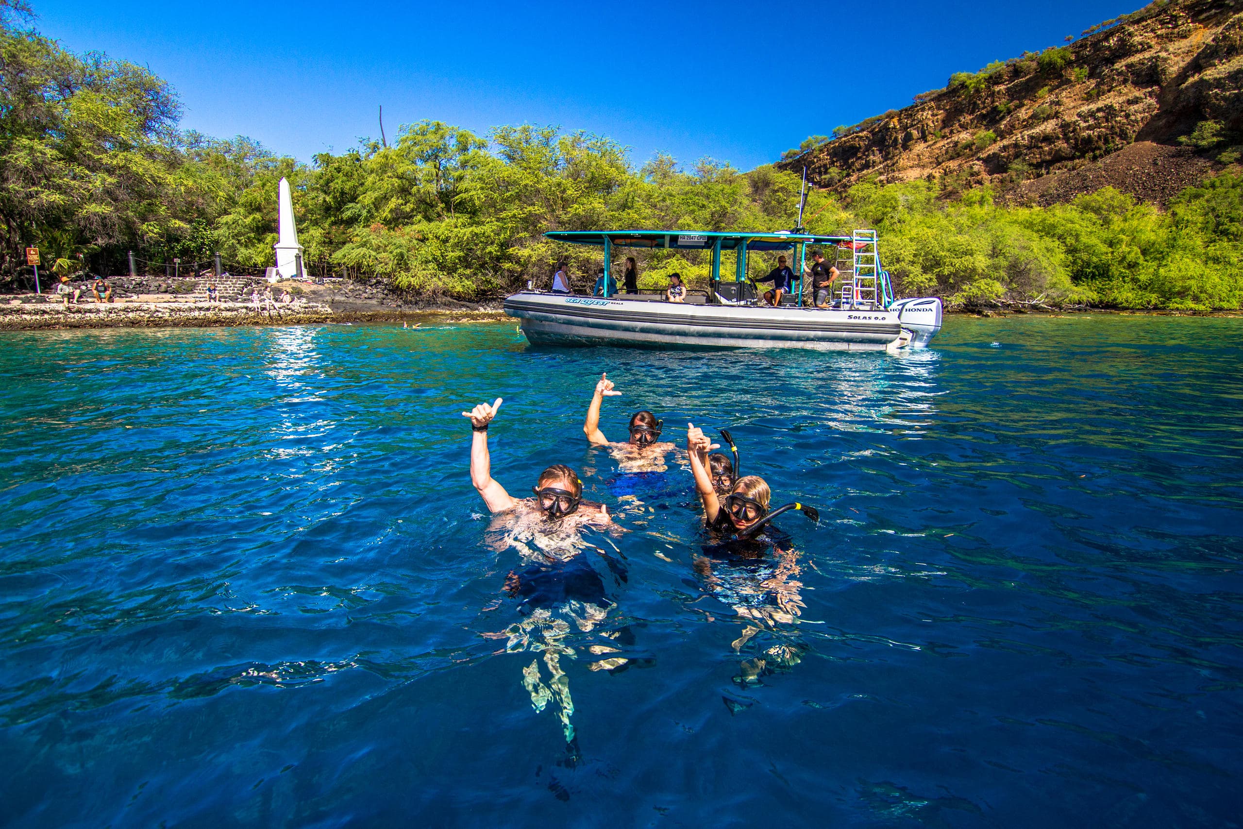 Snorkelers jumping from boat into clear Hawaiian reef waters
