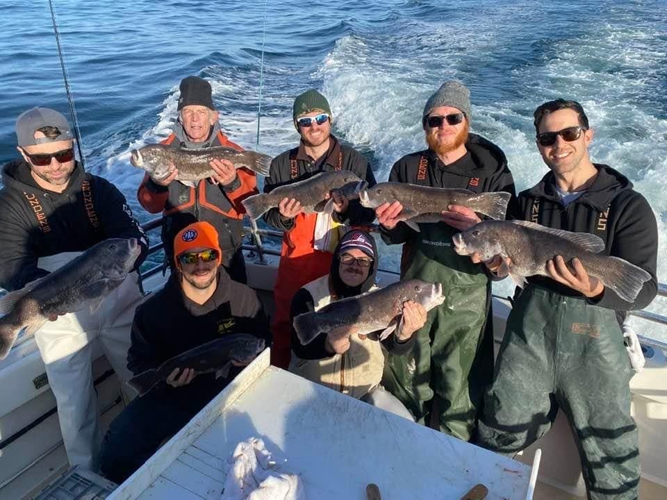 Crew holding mixed catches on boat with ocean wake behind