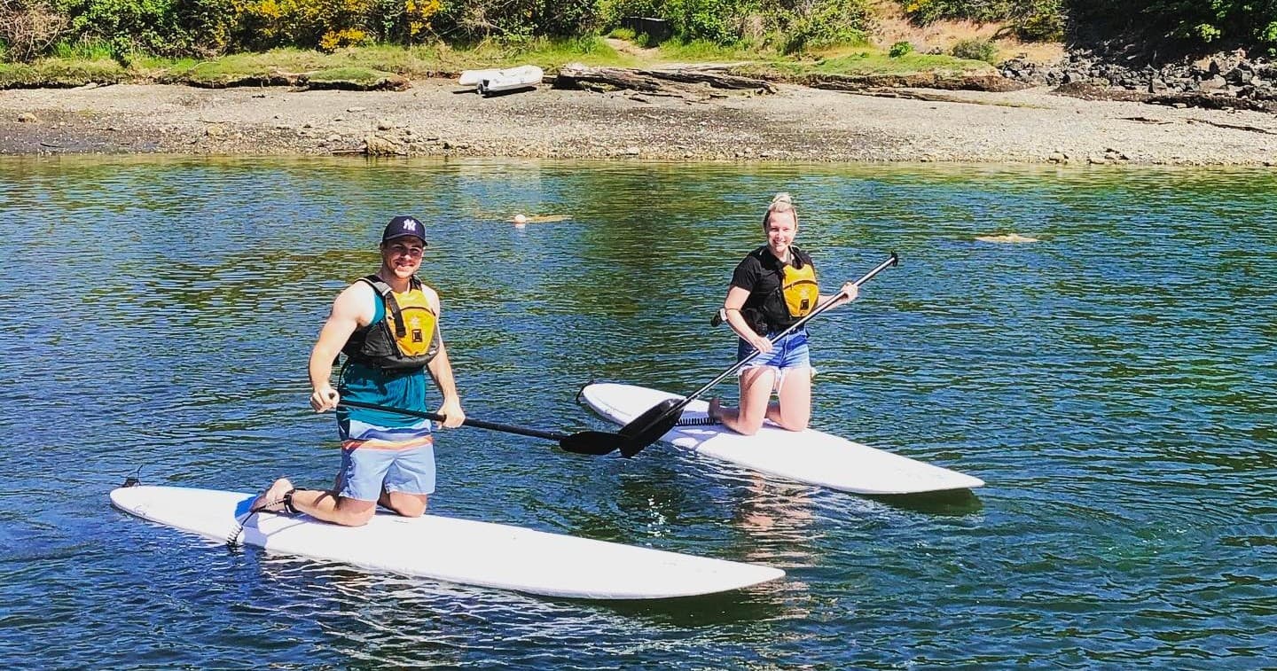 Two stand-up paddleboarders enjoying calm estuary waters