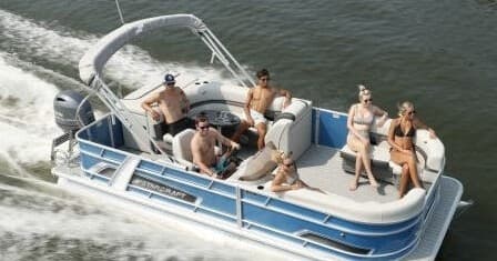 Pontoon boat full of friends enjoying daytime river cruise near shore