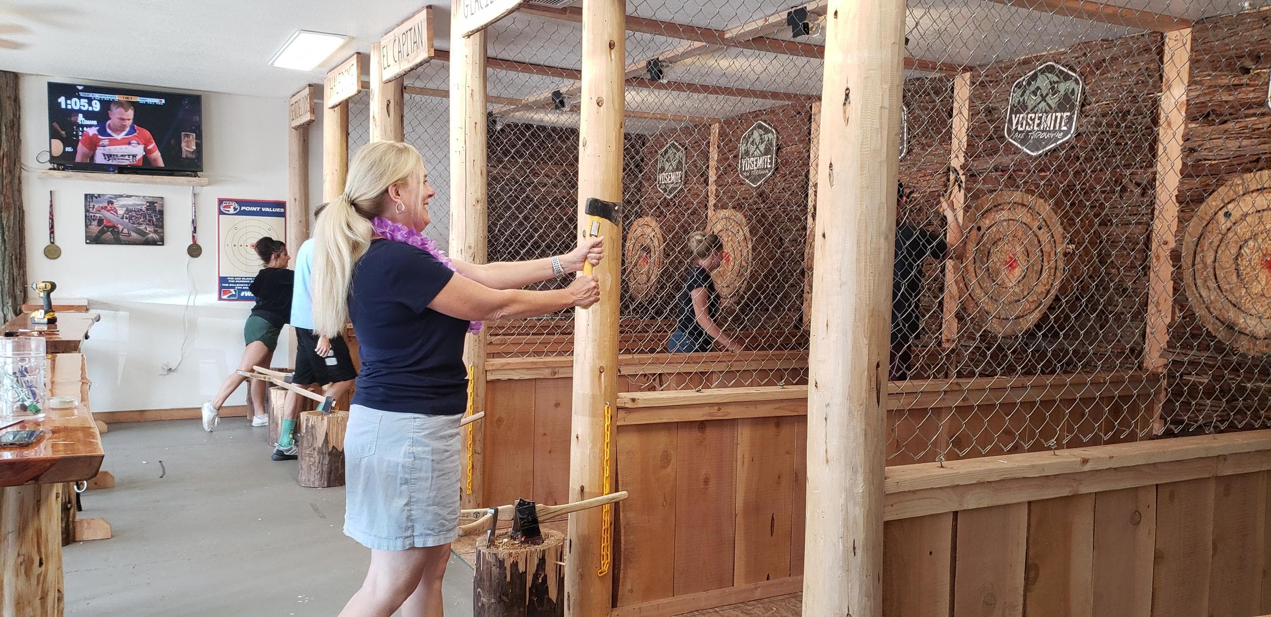 Woman preparing to toss axe at indoor lane behind safety net